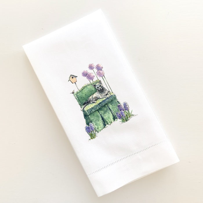 Grey kitty on green topiary chair surrounded by hyaciths, alliums and a little wren.