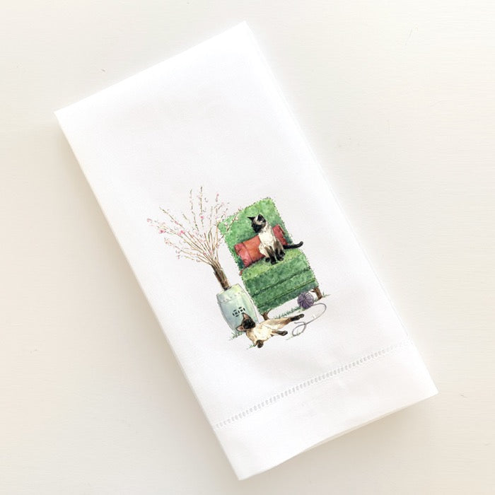 Topiary chair with two Siamese cats sitting for a portrait with ceramic garden stool, apple blossoms and a ball of yarn.