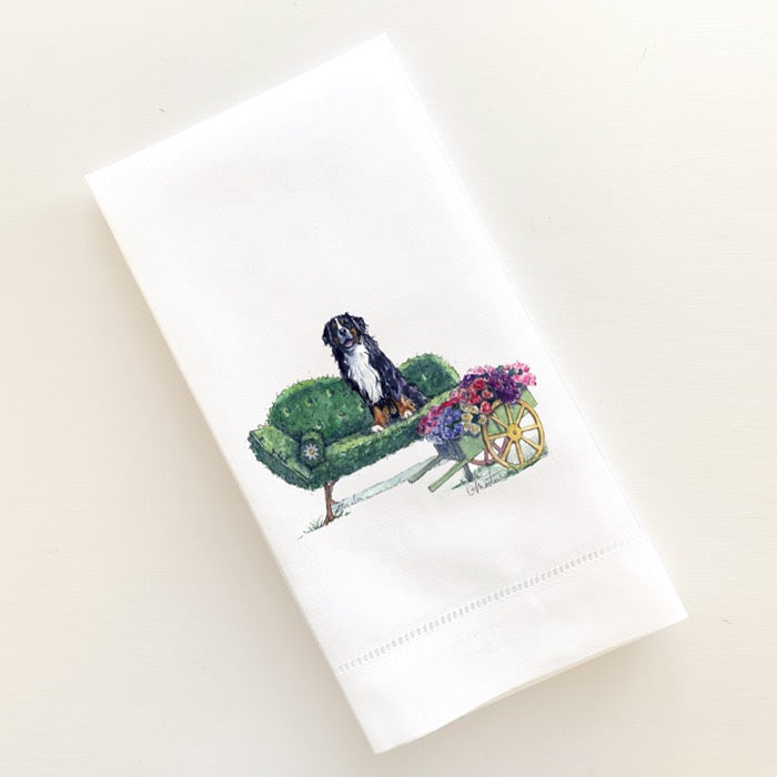 Linen guest towel with Bernese Mountain Dog sitting on topiary couch next to cart overflowing with flowers.