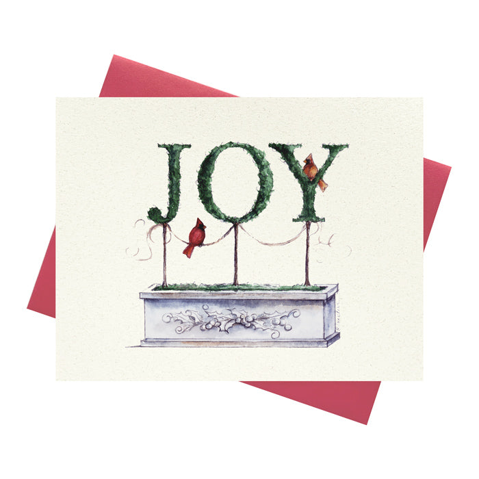 JOY spelled out in topiary with holiday cardinals on greeting card with red envelope.